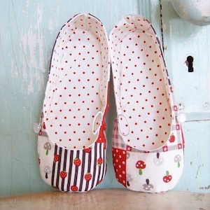 May include: A pair of red and white fabric shoes with a polka dot pattern on the inside. The shoes have a patchwork design on the outside with strawberries, mushrooms, and checkered patterns.