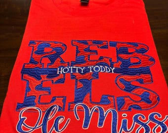May include: Red t-shirt with blue and red embroidered lettering that says "REBS HOTTY TODDY OLE MISS".