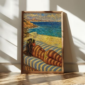Puede incluir: Una pintura enmarcada representa a una persona tomando el sol en una tumbona a rayas azules y amarillas, con un paisaje costero al fondo. La obra de arte presenta una paleta de colores cálidos, con el sol proyectando sombras rayadas sobre el cuerpo.