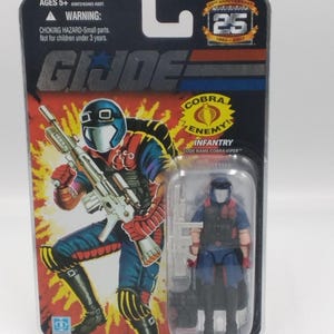 Pode incluir: Figura de ação G.I. Joe Cobra Viper na embalagem original. A embalagem apresenta uma ilustração da personagem com uma arma e o texto "COBRA ENEMY! INFANTRY". A figura está numa caixa de plástico transparente.