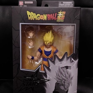 Puede incluir: Figura de acción de Dragon Ball Super Super Saiyan 2 Goku en caja. La figura tiene cabello amarillo puntiagudo, un atuendo naranja y azul, y viene con manos intercambiables. La caja presenta el logotipo de Dragon Ball Super y el texto "Super Saiyan 2 Goku".