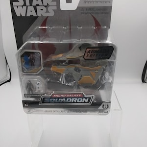 May include: A Star Wars Micro Galaxy Squadron toy featuring Anakin Skywalker's Jedi Interceptor. The toy is in a clear plastic package with the Star Wars logo and Episode III branding. The ship is grey and yellow.