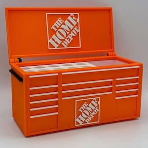 May include: An orange toolbox with a hinged lid and multiple drawers. The Home Depot logo is displayed on the lid and front of the toolbox in white. The toolbox has a black handle and white stripes on the drawers.