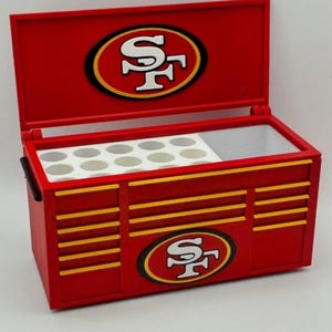 Può includere: Contenitore termico rosso a forma di cassetta degli attrezzi con il logo dei San Francisco 49ers. Il contenitore ha un coperchio incernierato e strisce gialle. Il logo è sul coperchio e sulla parte anteriore. All'interno, ci sono scomparti bianchi.