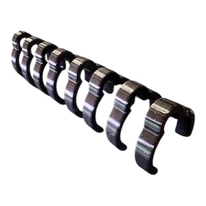 May include: A series of black metal binder rings, each with a curved, open design. The rings are arranged in a line, slightly angled, against a white background. The metal has a shiny, reflective surface.