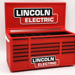 Può includere: Una cassetta degli attrezzi in miniatura rosso brillante con coperchio incernierato, caratterizzata dal logo Lincoln Electric in bianco e nero sul coperchio e sul pannello frontale. Presenta diversi frontali di cassetti stampati con bordi neri.