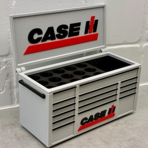 May include: A small white and grey toolbox, featuring the "CASE II" logo in black and red. The toolbox has a hinged lid and several drawers. Inside, there's a black insert with circular compartments.