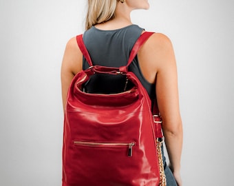 May include: A vibrant red leather backpack with gold-toned zippers and a chain accent. The bag features adjustable straps and a top handle. The design is sleek and modern, suitable for everyday use.