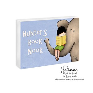 Op de afbeelding: Een blauwe en witte illustratie van een jongen die op de rug van een olifant zit en een boek leest. De tekst "Hunter's Book Nook" is geschreven in een speels lettertype.