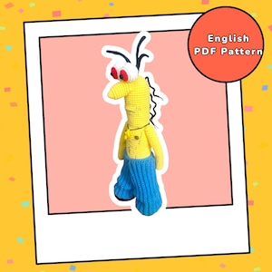 Puede incluir: Una muñeca de ganchillo hecha a mano con un diseño caprichoso. La muñeca tiene un cuerpo amarillo, pantalones azules y ojos rojos. La muñeca tiene antenas negras y un collar. La imagen incluye un círculo rojo con el texto "English PDF Pattern".