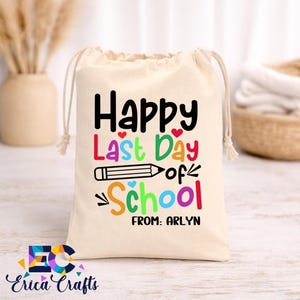 May include: A beige drawstring bag with the text "Happy Last Day of School" in various colors, a pencil graphic, and the name "Arlyn". The bag is made of a soft material and is perfect for gifting.