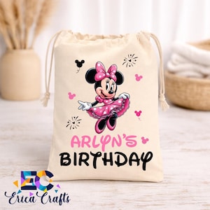 May include: A beige drawstring bag featuring a Minnie Mouse graphic in pink and black. The text "ARLYN'S BIRTHDAY" is printed in pink and black. The bag has a white drawstring closure and is decorated with Minnie Mouse icons.