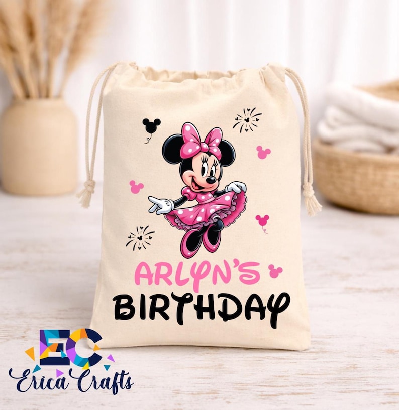 May include: A beige drawstring bag featuring a Minnie Mouse graphic in pink and black. The text "ARLYN'S BIRTHDAY" is printed in pink and black. The bag has a white drawstring closure and is decorated with Minnie Mouse icons.