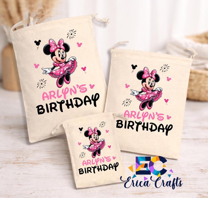 May include: Three beige drawstring bags with a Minnie Mouse design. Each bag features a pink Minnie Mouse illustration, the text "ARLYN'S BIRTHDAY" in pink and black, and decorative accents. The bags vary in size.