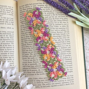 My 'Janessa' Version 3 bookmark in peach, purple, yellow and leaf green cotton thread on an open page of a book.