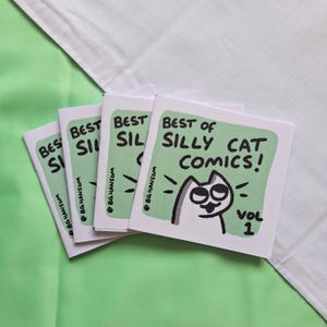 May include: A stack of four square booklets titled Best of Silly Cat Comics! Vol 1. Each white cover features a light green rectangular background with a black ink illustration of a cat with wide eyes and the text @BGHANSOM printed vertically.
