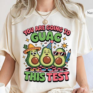 May include: A white t-shirt with a graphic of three cartoon avocados wearing party hats and the text "You are going to guac this test".