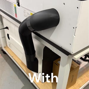 May include: A white and black laser machine with a black flexible hose attached. The hose is connected to the machine's side. The text "With adapters installed" is overlaid on the image. The machine sits on a white table.