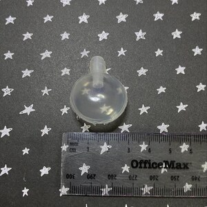 May include: A clear plastic squeaky dog toy shaped like a ball with a small hole at the top. The toy is about 2.5 inches in diameter.