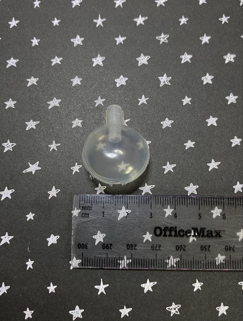 May include: A clear plastic squeaky dog toy shaped like a ball with a small hole at the top. The toy is about 2.5 inches in diameter.
