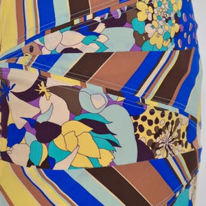Puede incluir: Falda estampada con dise&ntilde;o patchwork. La falda presenta una vibrante mezcla de colores que incluyen amarillo, azul, marr&oacute;n y morado, con estampados florales y de rayas. La falda tiene una silueta ajustada.
