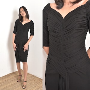 May include: A black, form-fitting dress with a sweetheart neckline and ruched detailing. The dress has a fitted bodice and a flowing skirt.