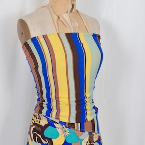 Puede incluir: Conjunto de dos piezas en maniqu&iacute;, compuesto por un top tubo y una falda. El top presenta rayas verticales en azul, amarillo, marr&oacute;n y verde. La falda tiene un colorido estampado floral y abstracto con tonos azules, morados y marrones. Dise&ntilde;o vibrante y llamativo.
