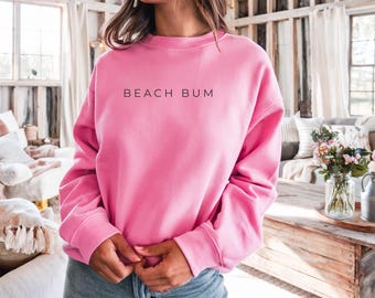 Può includere: Una felpa rosa acceso con la scritta "BEACH BUM" in nero. Questo top casual girocollo è a tinta unita e ha maniche lunghe. Un capo comodo per l'uso quotidiano.