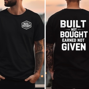 Könnte beinhalten: Schwarzes T-Shirt mit weißem Text auf der Rückseite: „BUILT NOT BOUGHT EARNED NOT GIVEN“. Auf der Vorderseite des T-Shirts steht „BUILT DIFFERENT“ in einem weißen Sechseck. Das T-Shirt ist kurzärmelig.