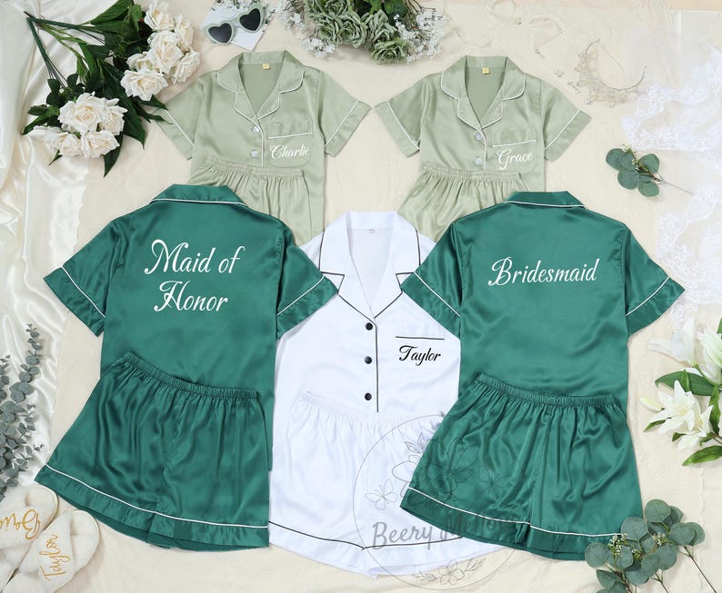 May include: Matching pajama sets in green and white, perfect for a bridal party. The sets include short-sleeved button-down shirts and shorts. Some shirts are embroidered with names and titles like "Maid of Honor" and "Bridesmaid."