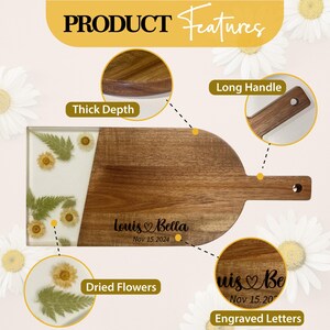 May include: A wooden serving board with a long handle, a white epoxy resin section with dried flowers, and engraved lettering that reads "Louis Bella Nov 15, 2024".