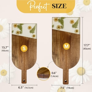 May include: Two wooden serving boards with a white epoxy top and pressed flowers. The smaller board measures 15.7 inches long and 6.5 inches wide. The larger board measures 17.7 inches long and 7.5 inches wide.