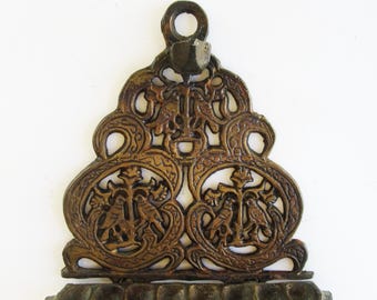Può includere: Applique da parete in metallo color bronzo con un design ornato. L'applique presenta una serie di motivi circolari e curvi, con due aree circolari contenenti motivi di uccelli e croci. Una fila di piccoli supporti appuntiti è nella parte inferiore.