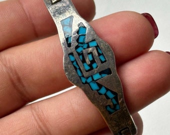 May include: A silver bracelet with a turquoise inlay design. The bracelet has a hinged clasp.