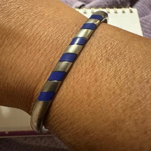 May include: A silver bangle bracelet with blue enamel stripes.