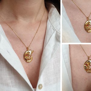 May include: A gold necklace with a pendant featuring a stylized fox design with red gemstones. The pendant is on a delicate chain.