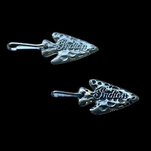May include: Two silver arrowhead-shaped keychains with the word "Indian" embossed on them.
