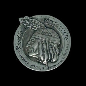 Peut inclure: Emblème de moto Indian en argent avec les mots "Indian Motorcycle" et "Hendee Mfg Co Springfield Mass USA" autour du bord.
