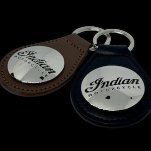 May include: Two leather keyrings with silver metal Indian Motorcycle logos. One keyring is brown leather and the other is black leather.