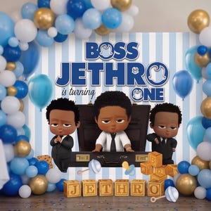 May include: A birthday party decoration featuring a Boss Baby theme. The scene includes a backdrop with the text "BOSS JETHRO is turning ONE", cartoon figures, balloons in blue, white, and gold, and wooden blocks spelling "JETHRO".