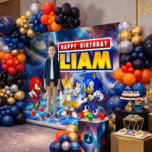 Peut inclure: Une toile de fond pour anniversaire avec un décor spatial représentant Sonic, Tails et Knuckles, le texte HAPPY BIRTHDAY LIAM, et une grande arche de ballons bleu marine, orange, dorés et noirs entourant l'ensemble de la décoration.