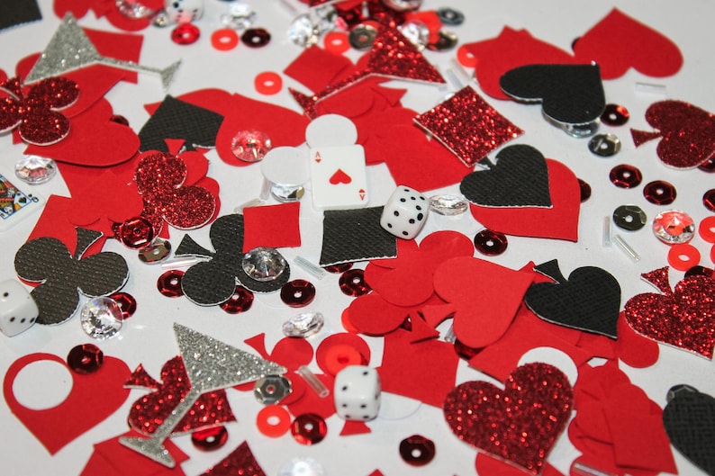 May include: A collection of red, black, and silver playing card and casino-themed confetti. Includes hearts, spades, clubs, diamonds, dice, and sequins. A playing card with the Ace of Hearts is visible.