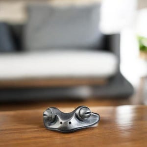 May include: A silver frog figurine with large, round eyes. The frog is sitting on a wooden surface.