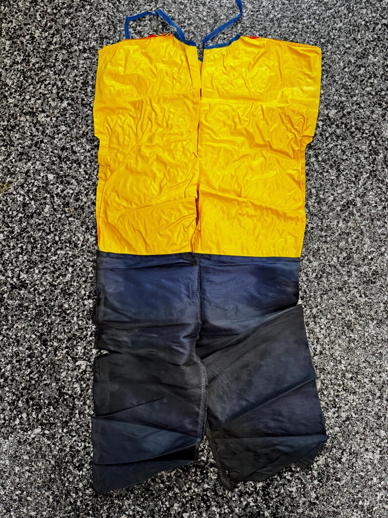 May include: A two-piece garment featuring a bright yellow sleeveless top with thin blue shoulder straps and a pair of dark navy blue pants. The top is solid yellow, while the pants are a deep, dark blue color with visible stitching.