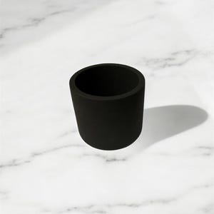Peut inclure: Un gobelet en silicone noir, parfait pour ranger de petits objets comme des bijoux ou des clés.