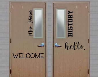 May include: Two wooden doors with rectangular glass panels. The left door reads "Miss. Johnson" and "WELCOME" in black script. The right door says "HISTORY" and "hello." in black. The doors have silver handles.