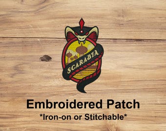 May include: Embroidered patch with a cobra design, featuring a red, black, and yellow color scheme. The patch includes the word "SCARABIA" on a black banner. The patch is iron-on or stitchable.