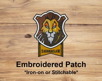 May include: Embroidered patch featuring a lion's head design in shades of brown, gold, and white, set against a shield shape. The text "SAVANACLAW" is displayed on a yellow banner. The patch is labeled "Embroidered Patch *Iron-on or Stitchable*".