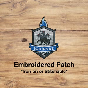May include: Embroidered patch with a black Cerberus design, three heads, red eyes, and a blue flame. The patch includes a blue banner with the text "IGNIHYDE" and is iron-on or stitchable.