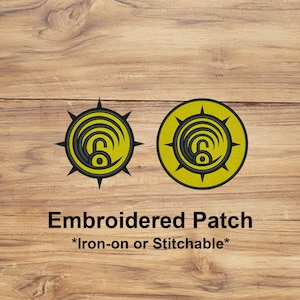 May include: Two embroidered patches with a yellow and black design. The patches feature a circular emblem with a stylized lock symbol. The text "Embroidered Patch" and "*Iron-on or Stitchable*" are displayed below the patches.